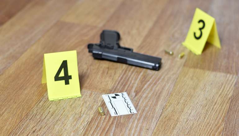 Crime scene investigation concept - Pistol and bullet shell against the yellow crime marker on