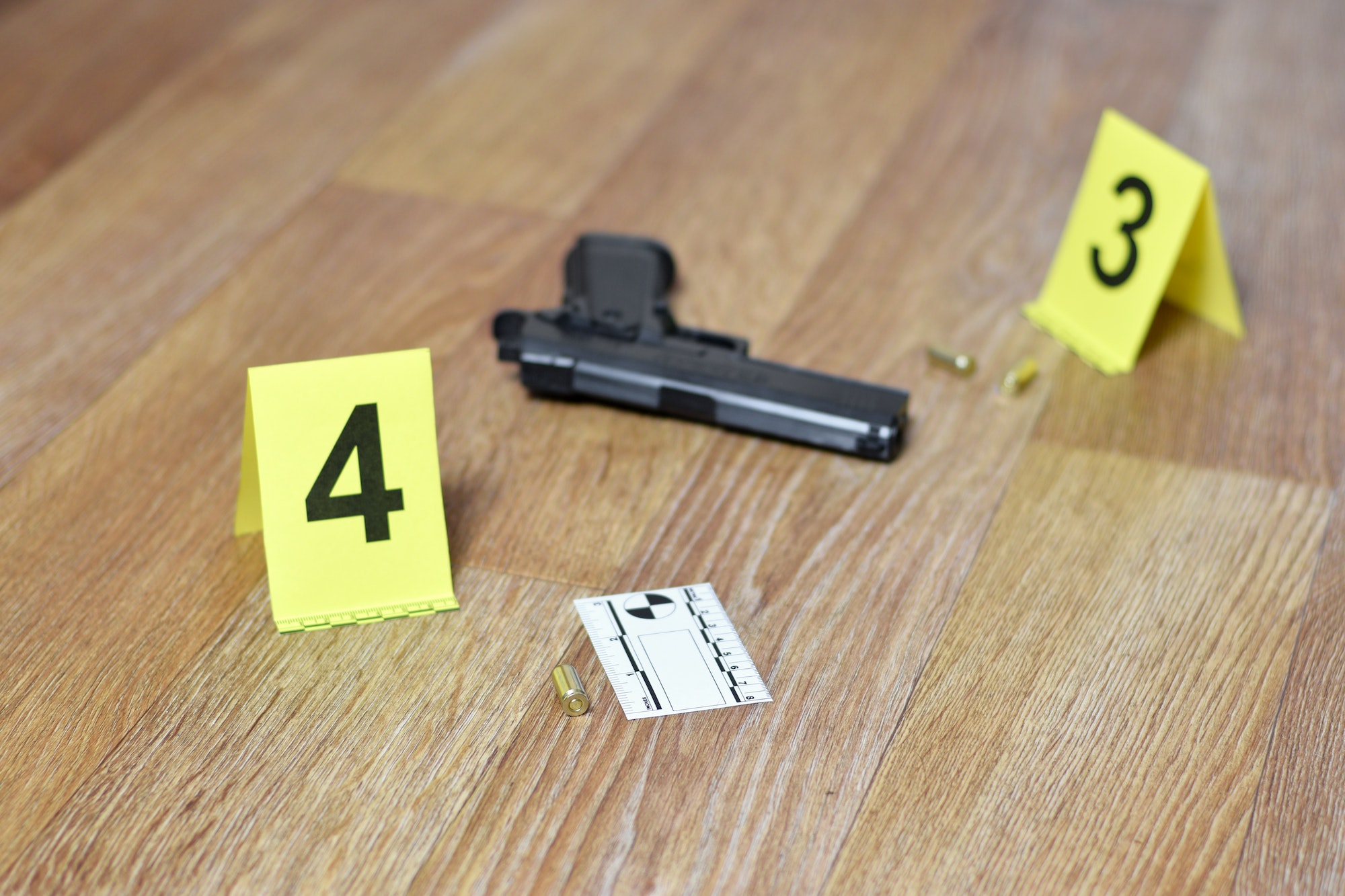 Crime scene investigation concept - Pistol and bullet shell against the yellow crime marker on