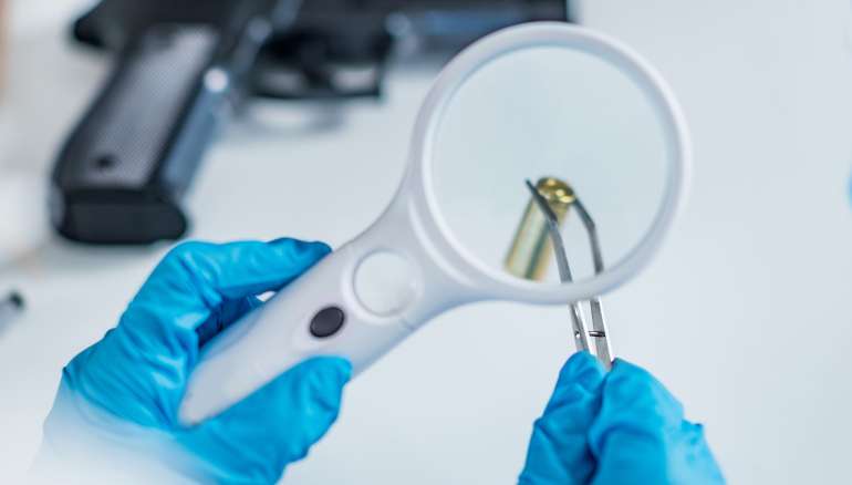 Forensic scientist examining bullet casing